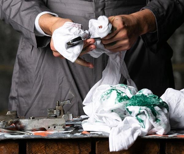 Worker cleaning a tool with a white industrial wiping cloth